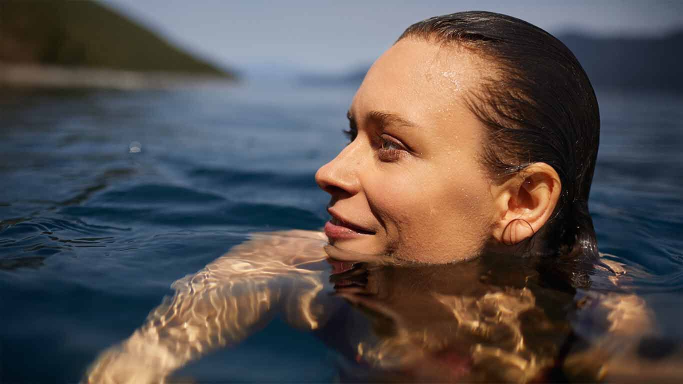 Close-up van een vrouw die in zee zwemt. Ze kijkt naar links.